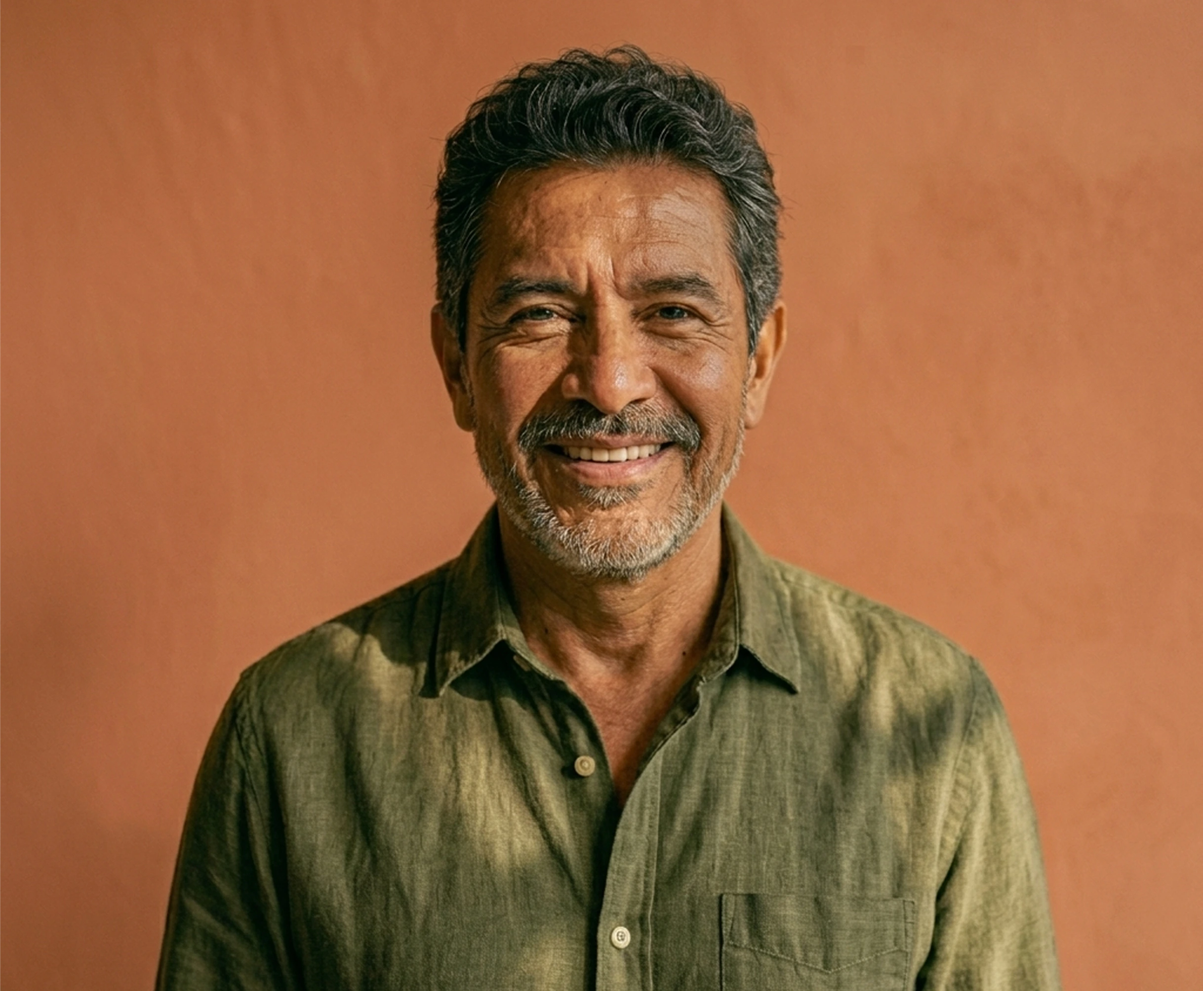 Man with graying hair, smiling in front of a beige wall